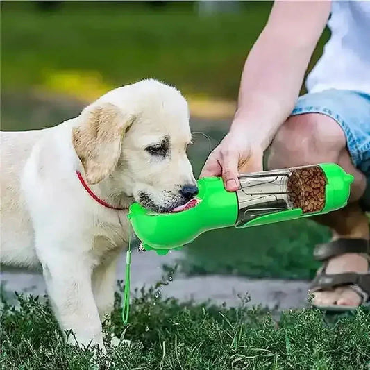 Un chiot qui boit dans un biberon multifonction 3 en 1 pour chiens, sur l’herbe, en laisse